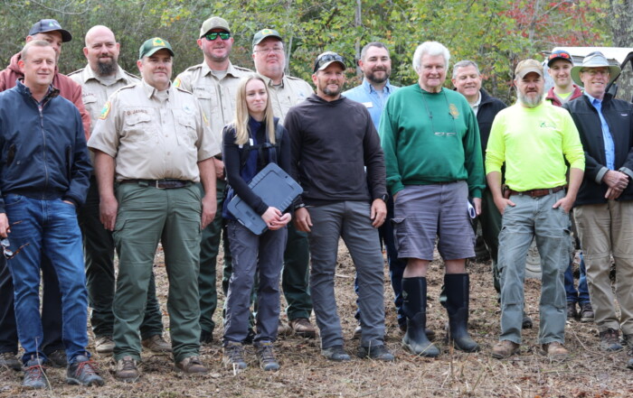 A group of people stands in an eastern deciduous forest